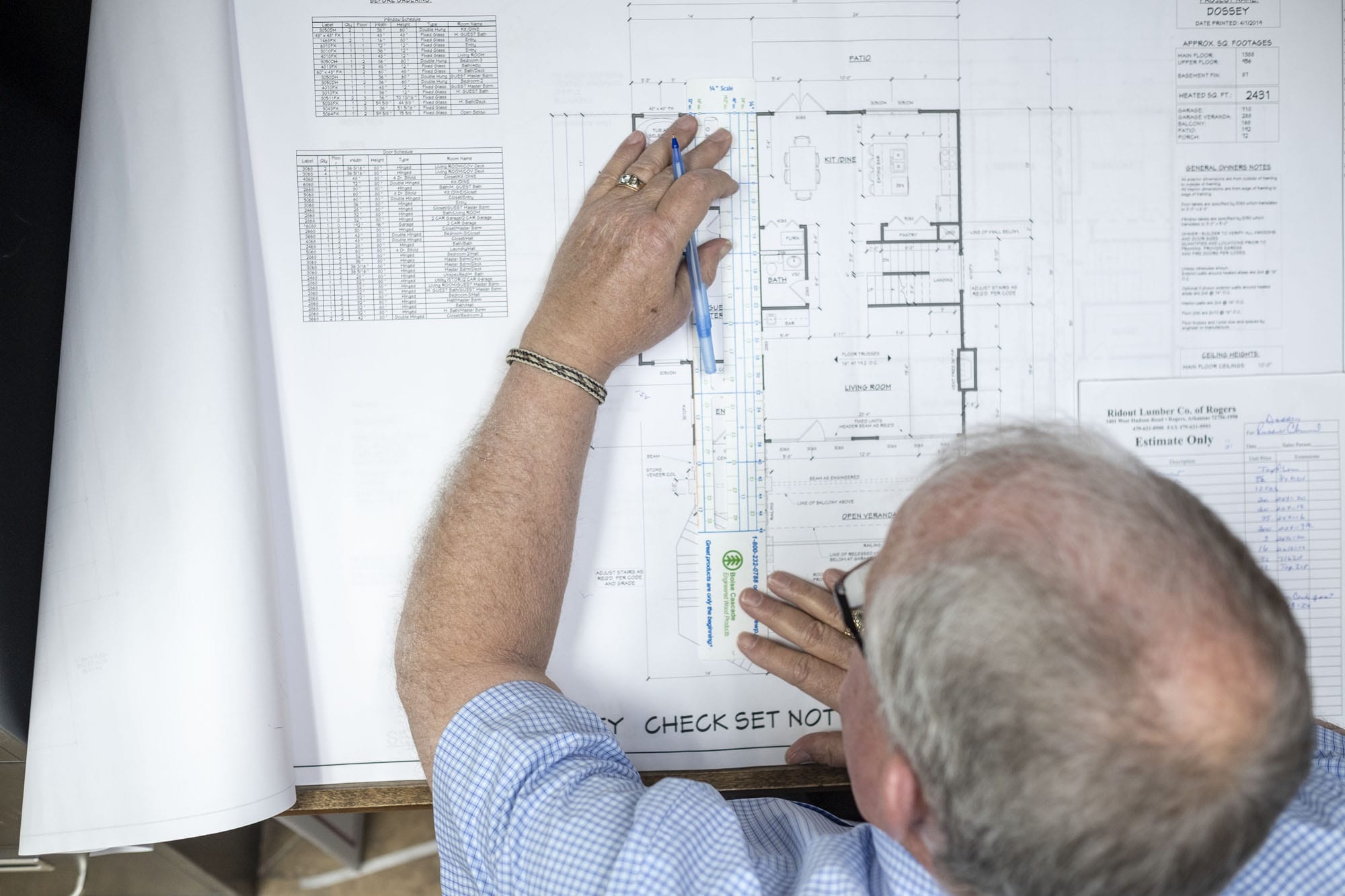 man holding architecture plans on a table