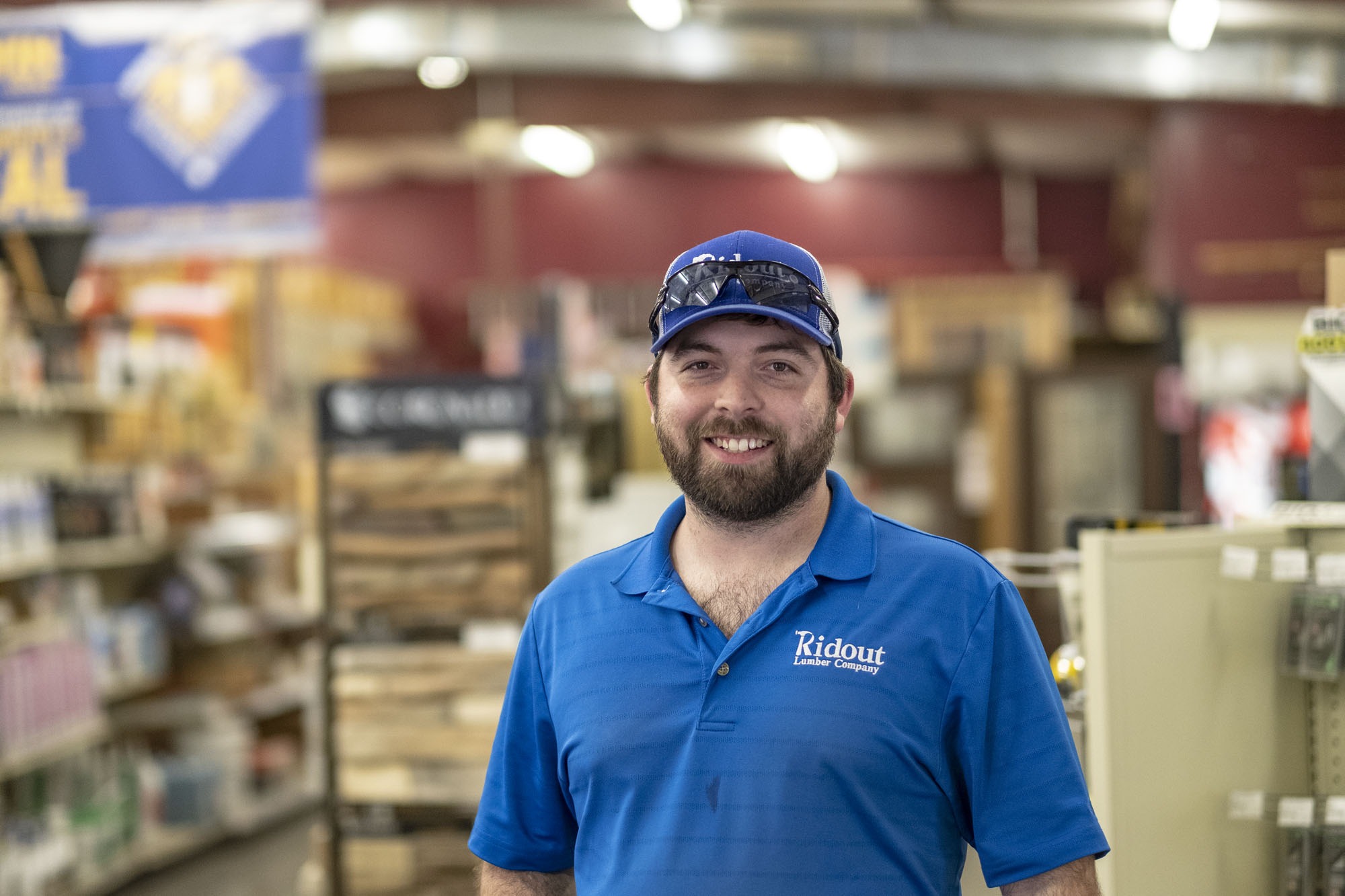 Smiling man with blue shirt and hat in a hardware store