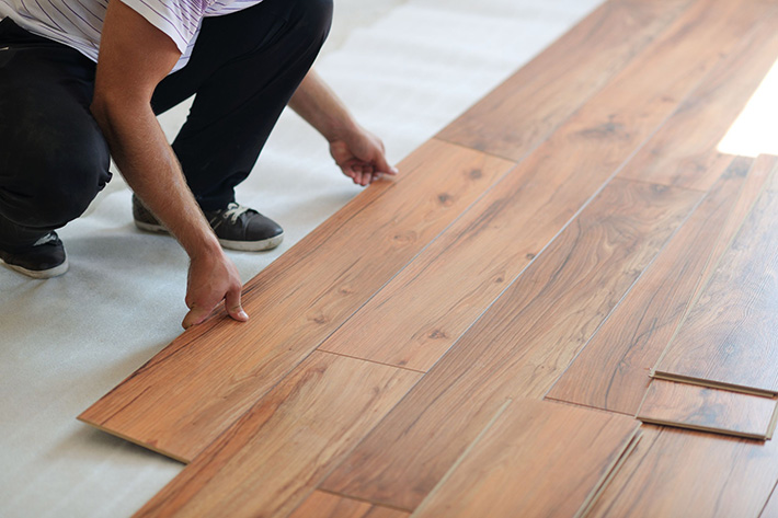 man installing wooden floors in house